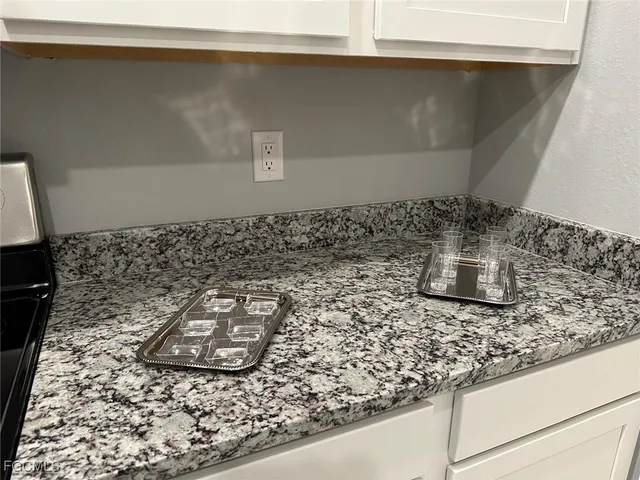 a kitchen with granite countertop white cabinets and stainless steel appliances