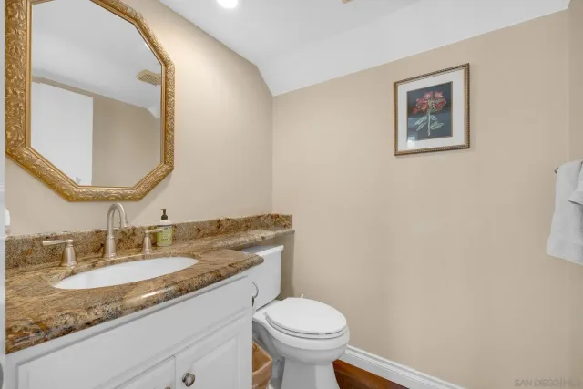 a bathroom with a granite countertop toilet sink and mirror