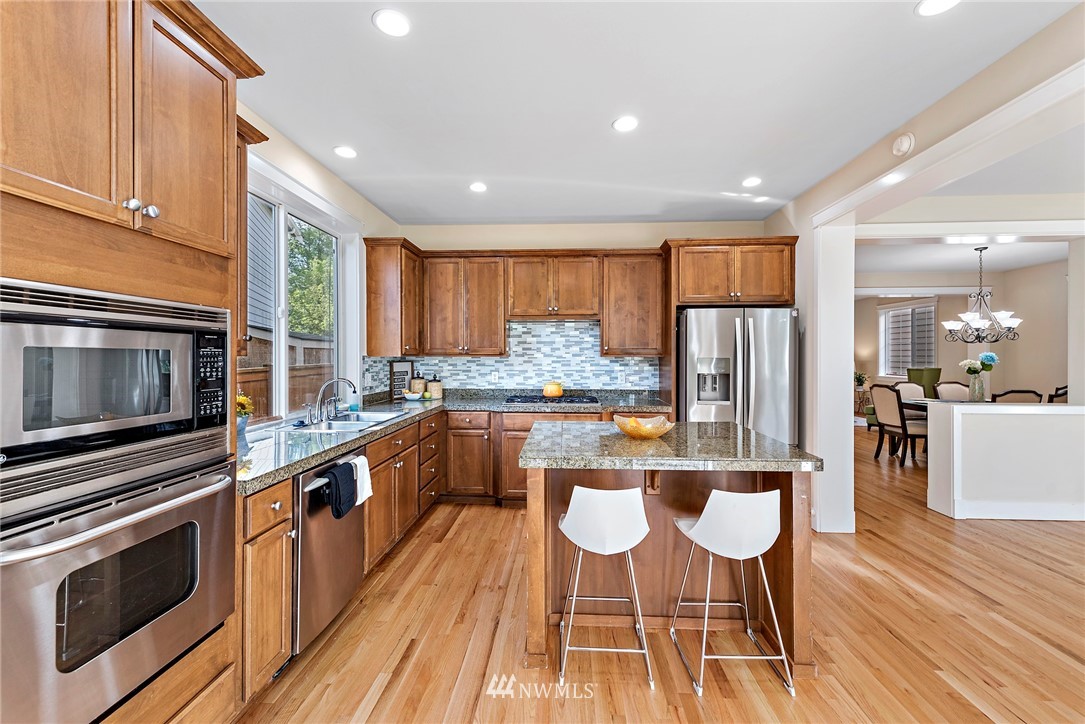 3915 167th Street Southeast Bothell, WA 98012 - Photo 11 of 28 a kitchen with stainless steel appliances a stove a sink a microwave a dining table and chairs