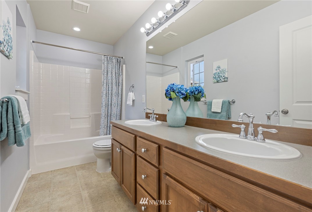 3915 167th Street Southeast Bothell, WA 98012 - Photo 21 of 28 a bathroom with a granite countertop sink a toilet a mirror and shower