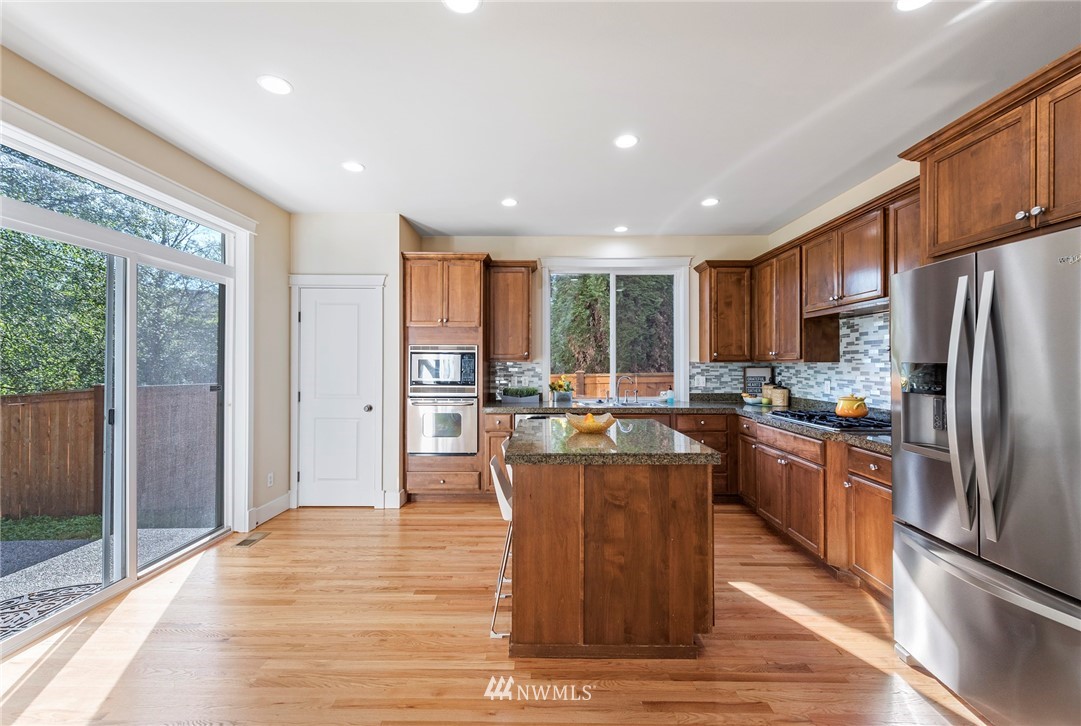 3915 167th Street Southeast Bothell, WA 98012 - Photo 10 of 28 a kitchen with stainless steel appliances granite countertop a refrigerator a sink dishwasher a stove and white cabinets with wooden floor