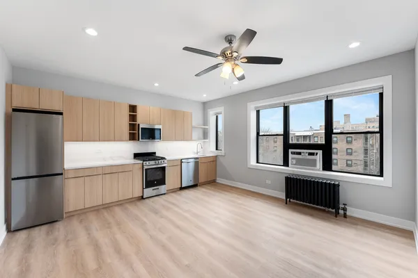 a kitchen with stainless steel appliances granite countertop a refrigerator a sink dishwasher a stove with white cabinets and wooden floor