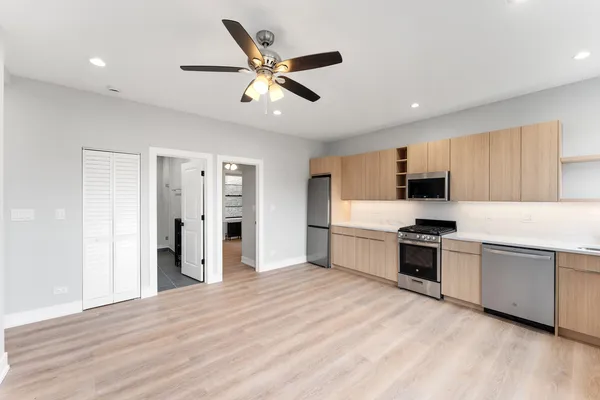 a kitchen with granite countertop a refrigerator oven a sink dishwasher and white cabinets with wooden floor