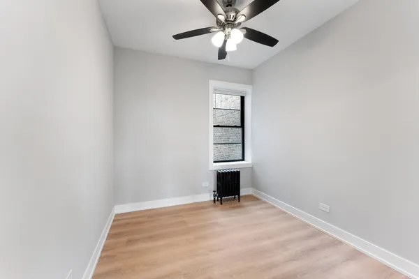 an empty room with windows and ceiling fan