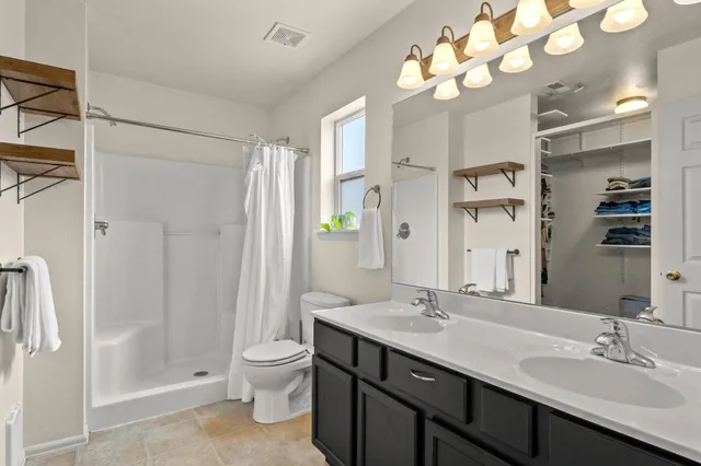 a bedroom with a bed and a lamp on dresser