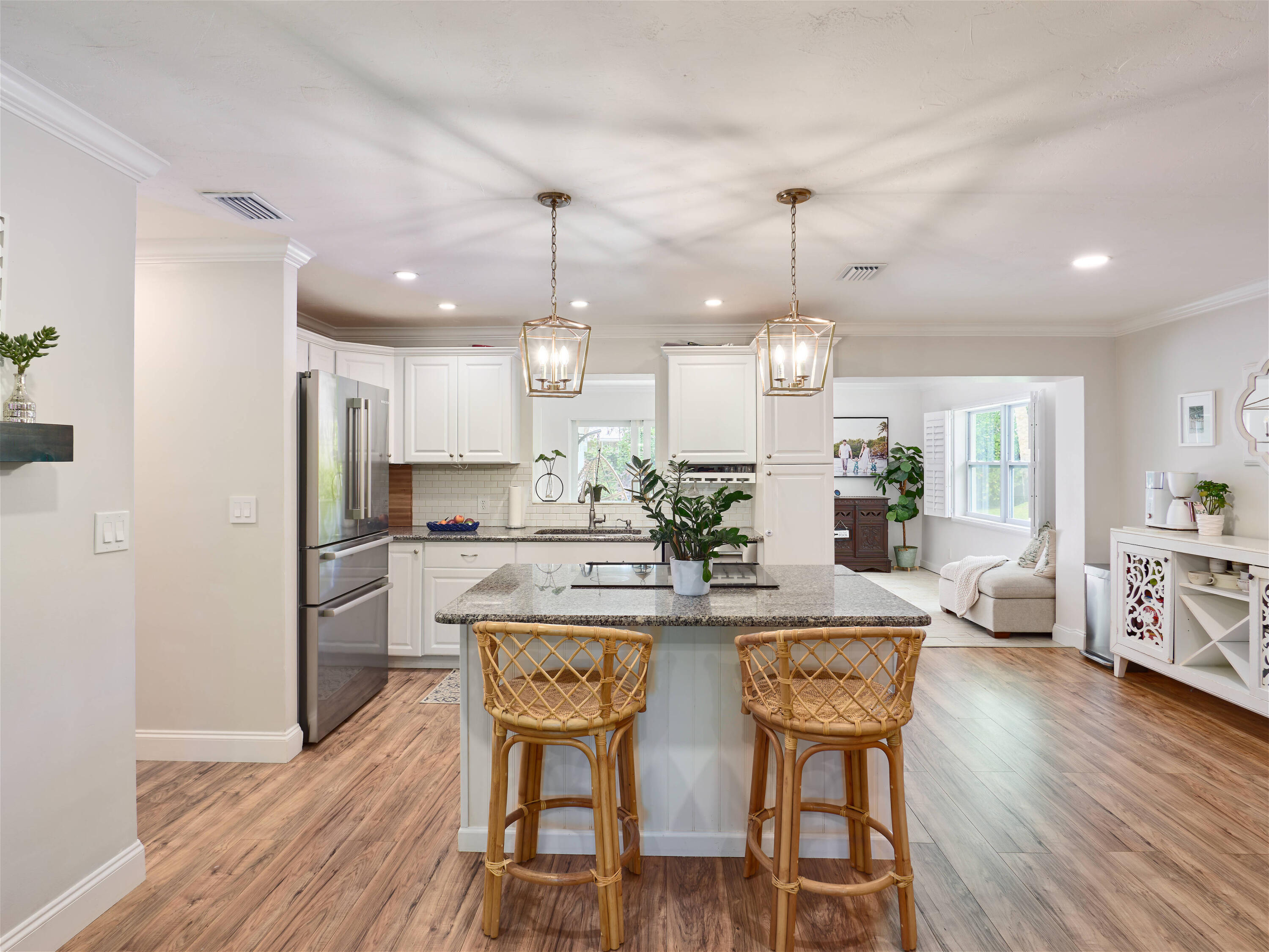 a kitchen with stainless steel appliances kitchen island granite countertop a dining table chairs and white cabinets