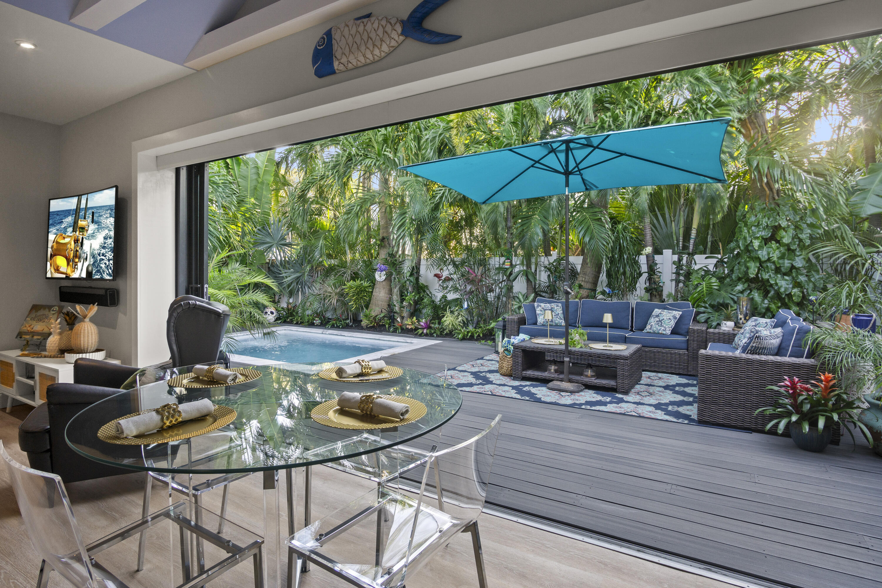 1616 Bertha Street, Unit 2 Key West, FL 33040 - Photo 12 of 45 a view of a patio with a dining table and chairs under an umbrella with a small yard