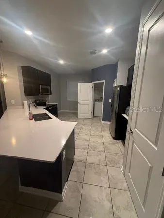 a large white kitchen with a sink a refrigerator and a mirror