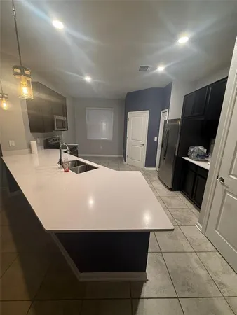 a large kitchen with a sink a counter space stainless steel appliances and cabinets