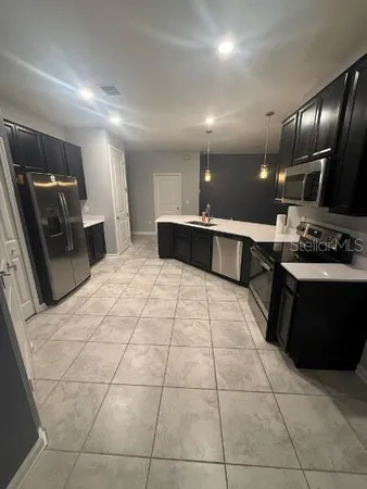 a large white kitchen with a large counter top a stove a sink and a refrigerator