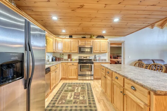 a kitchen with stainless steel appliances granite countertop a sink a stove and a microwave oven with cabinets