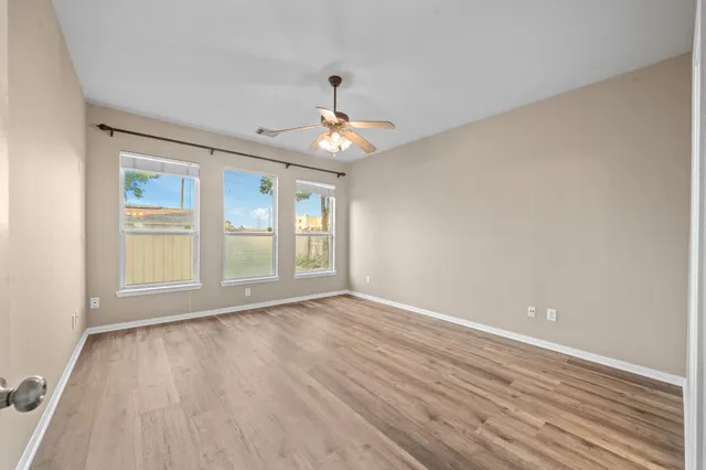 a view of an empty room with wooden floor and a window