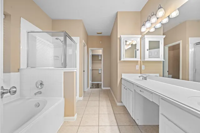 a spacious bathroom with a tub sink shower and mirror
