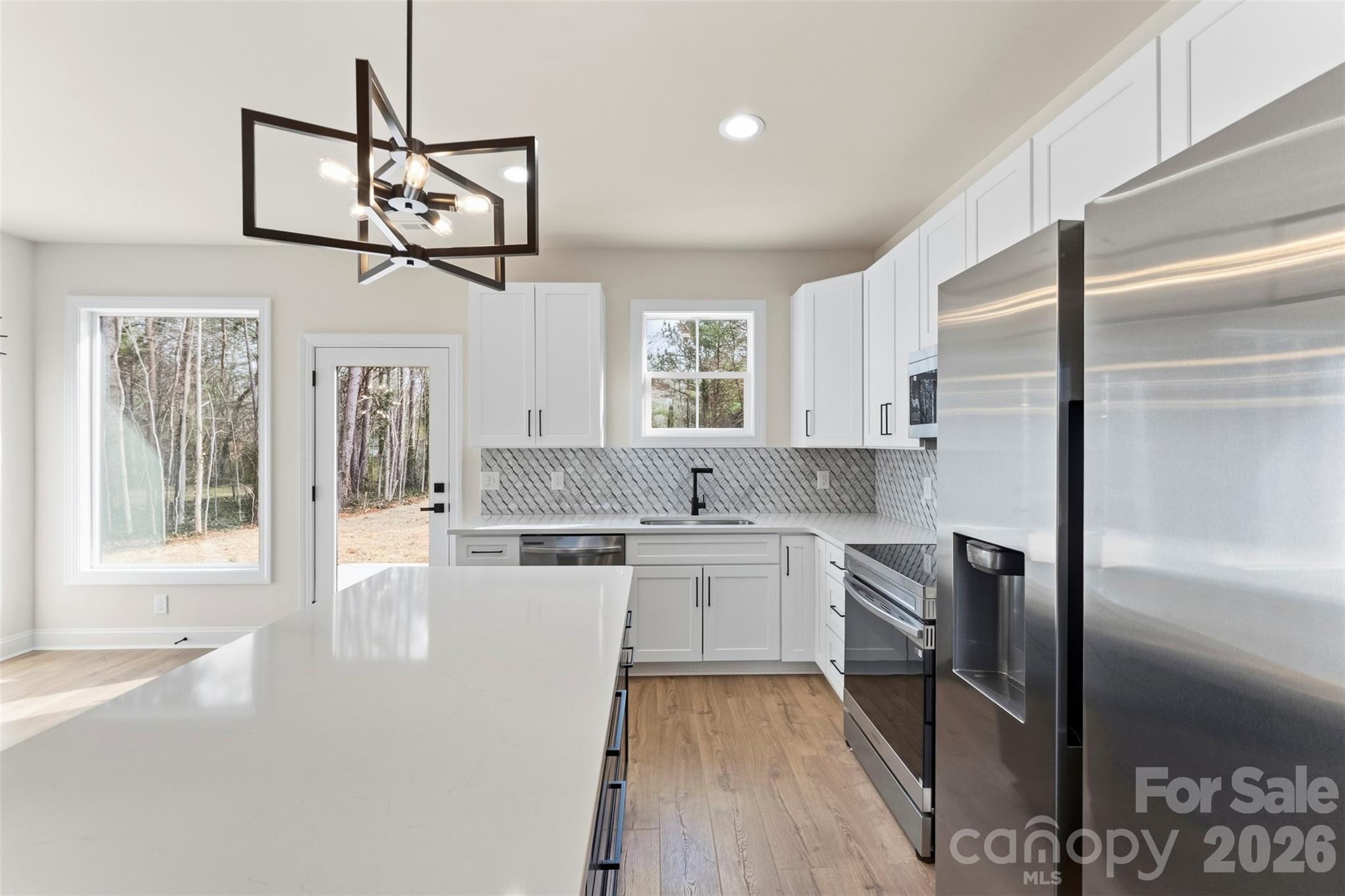1724 Barnhardt Road China Grove, NC 28023 - Photo 17 of 46 a kitchen with stainless steel appliances granite countertop a refrigerator a sink dishwasher a stove and white cabinets with wooden floor
