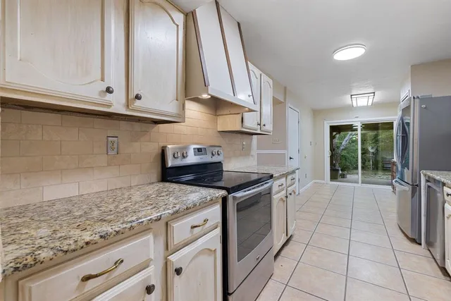 a kitchen with granite countertop a stove a sink and a refrigerator