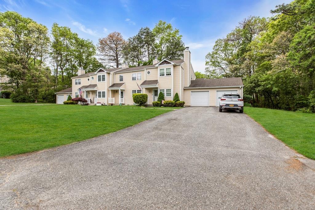 a view of a white house next to a yard and a large tree