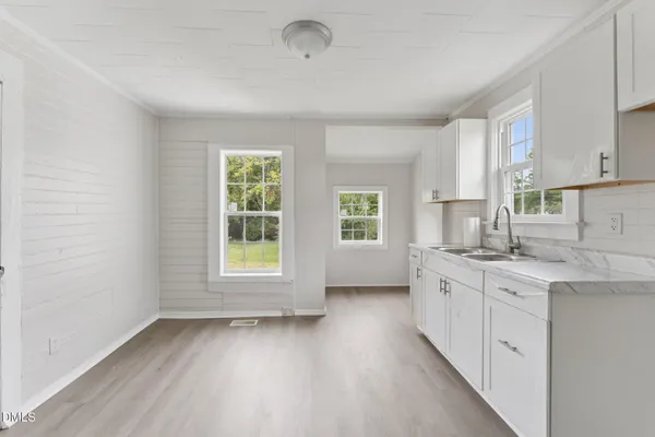 a kitchen with a sink cabinets wooden floor and a window