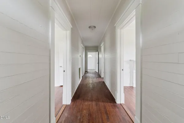 a view of a hallway with wooden floor and a bathroom