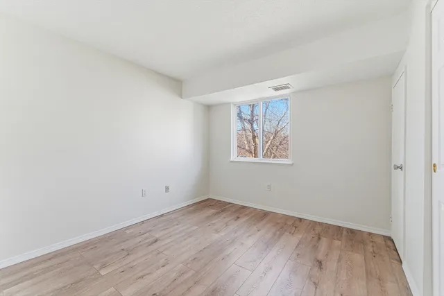 an empty room with wooden floor and window