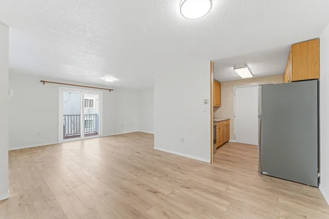 a view of a kitchen with wooden floor and a refrigerator