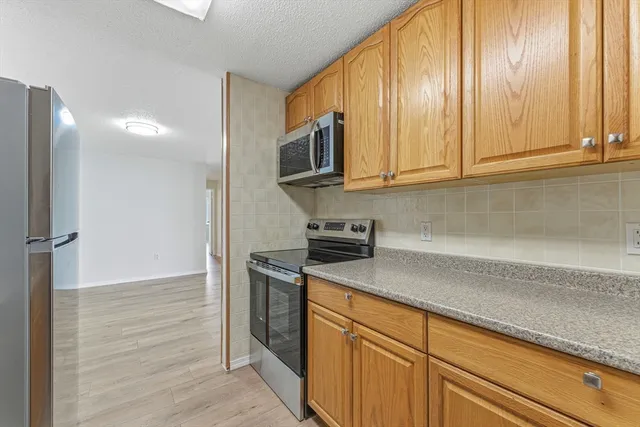 a kitchen with stainless steel appliances granite countertop a sink a stove and cabinets