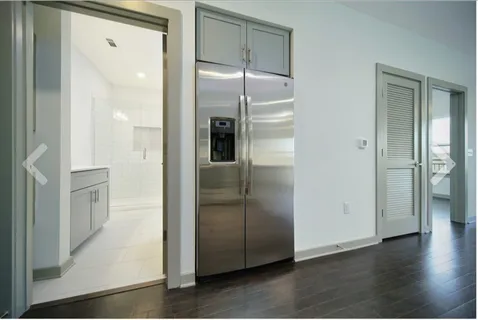 a view of a refrigerator in kitchen and an empty room