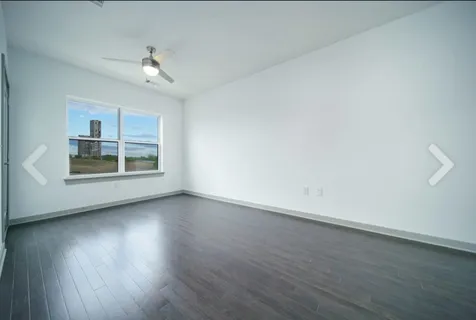 an empty room with wooden floor chandelier and windows