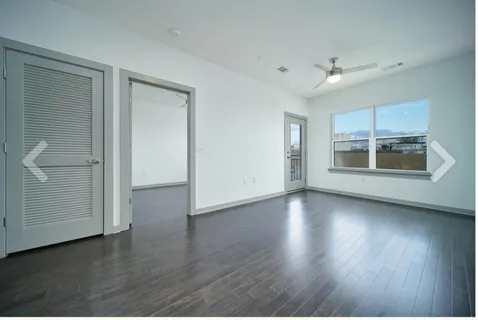 an empty room with wooden floor cabinet and windows