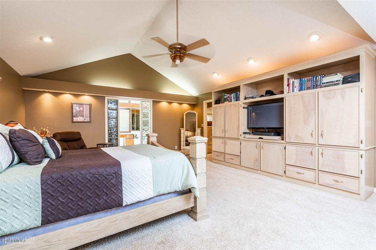 1225 Bass Road Macon, GA 31210 - Photo 21 of 58 a spacious bedroom with a large bed a flat screen tv and a ceiling fan