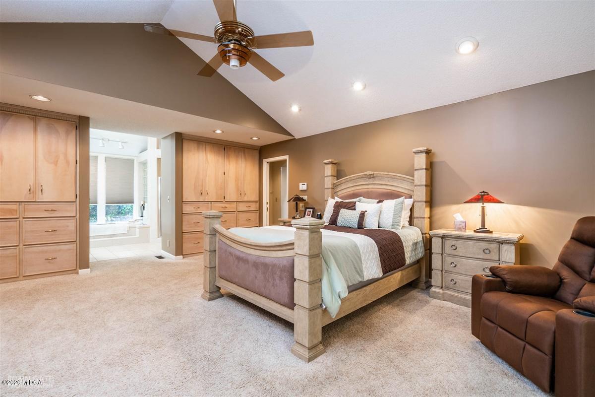 1225 Bass Road Macon, GA 31210 - Photo 22 of 58 a spacious bedroom with a bed a couch and a chandelier