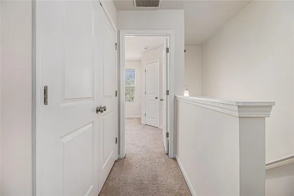 a view of a hallway with closet and a bathroom