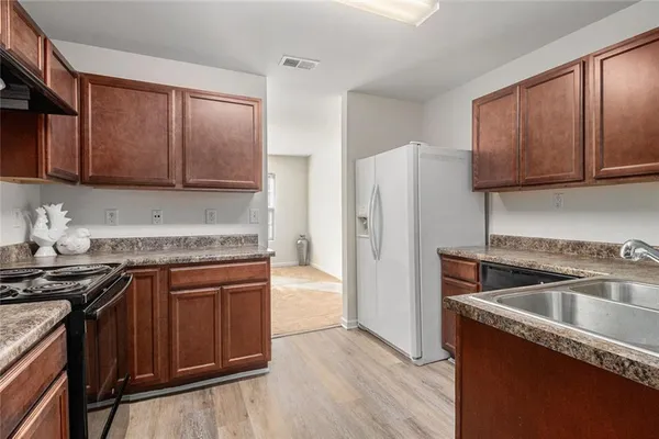 a kitchen with granite countertop a refrigerator stove and sink