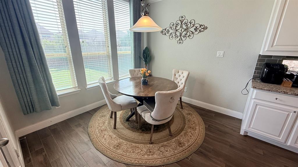 337 Prairie Ridge Lane Lewisville, TX 75056 - Photo 8 of 28 a dining room with furniture wooden floor a rug a potted plant and a fireplace