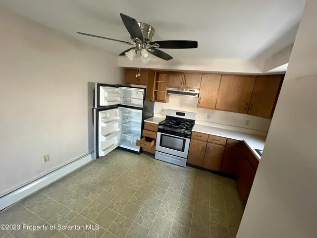 a view of kitchen and empty room with wooden floor
