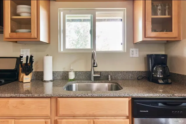 a kitchen with granite countertop a sink a stove and cabinets