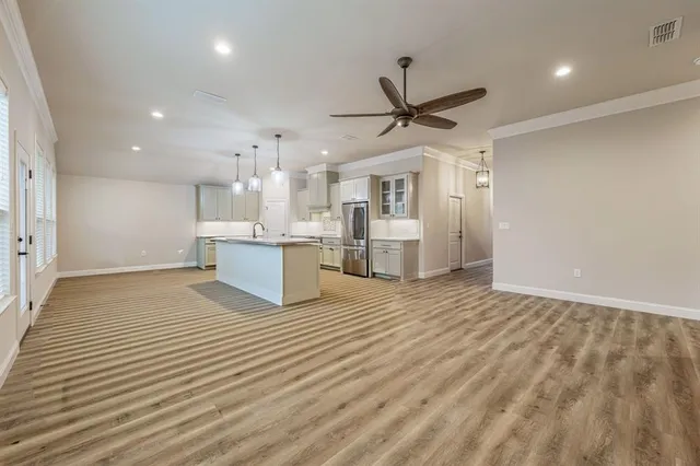 a view of kitchen and empty room with wooden floor and windows