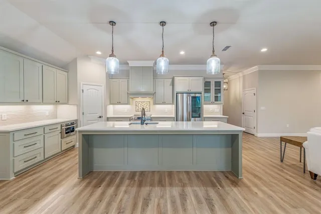 a large room with kitchen island a sink and a wooden floor