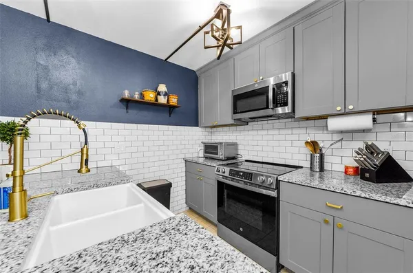 a kitchen with stainless steel appliances granite countertop a sink a stove top oven a chimney and cabinets