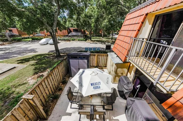 a view of a roof deck with table and chairs a barbeque with wooden floor and fence