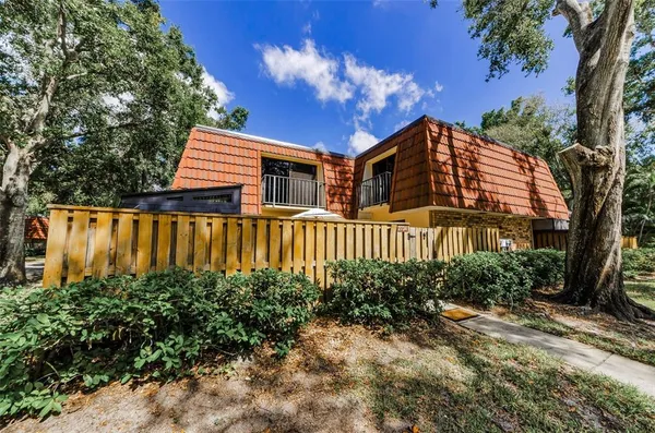 a view of a house with brick walls and flower plants next to a road