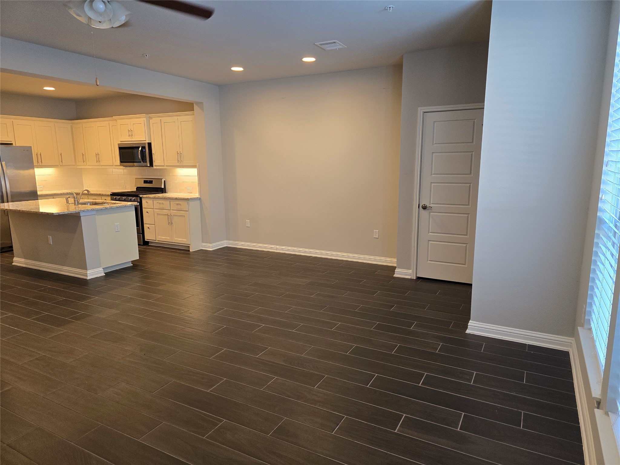 13800 Lyndhurst Street, Unit 233 Austin, TX 78717 - Photo 12 of 38 Kitchen with stainless steel appliances, recessed lighting, white cabinetry, an island with sink, and light stone counters