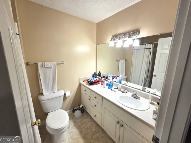 a bathroom with a sink a toilet a mirror a lamp and vanity