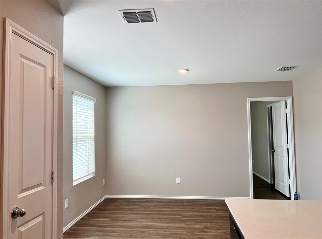 1103 Wildflower Street Ennis, TX 75119 - Photo 5 of 15 a view of an empty room with wooden floor and a window