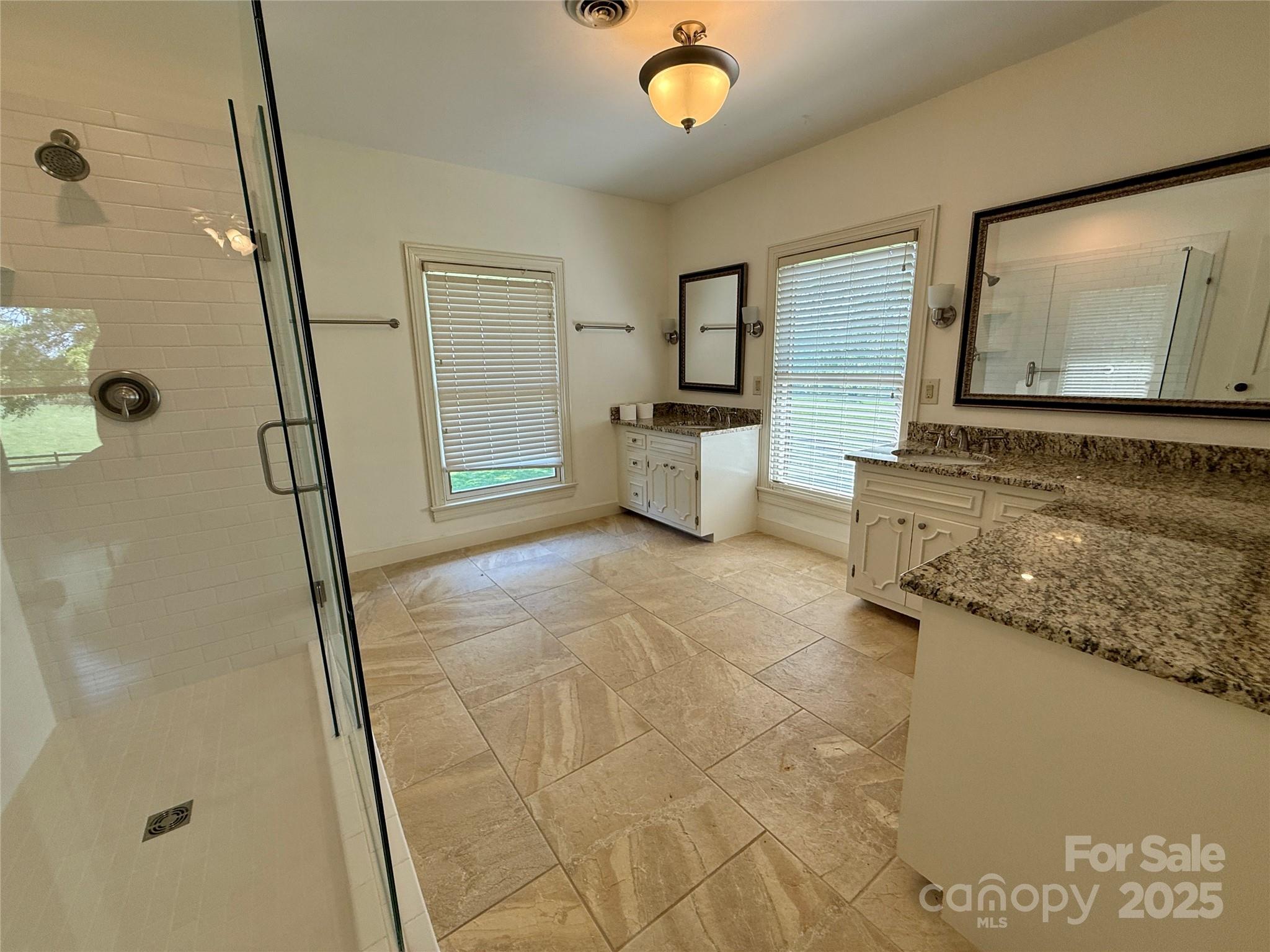 820 Phillips Road Columbus, NC 28722 - Photo 25 of 32 a spacious bathroom with a granite countertop sink a mirror and shower