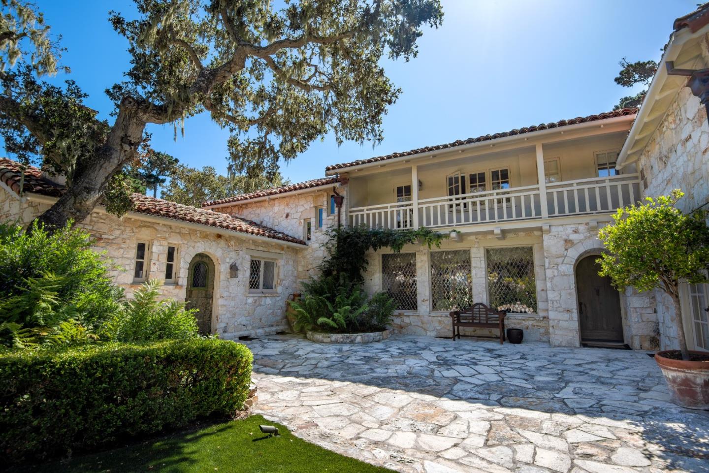 1456 Riata Road Pebble Beach, CA 93953 - Photo 1 of 32 a view of a white house next to a yard with plants and palm trees