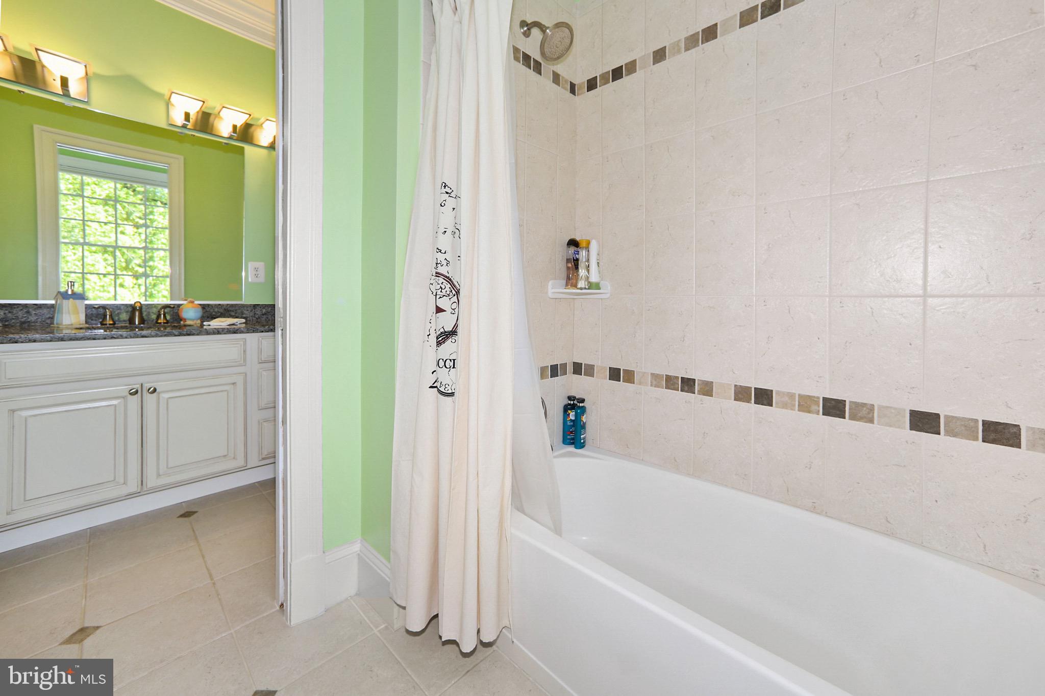 7117 Exfair Road Bethesda, MD 20814 - Photo 26 of 42 a bathroom with a bathtub a sink a window and a shower