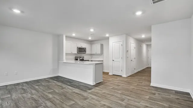 a view of large kitchen with granite countertop a sink and white cabinets