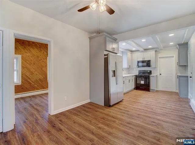 a view of a kitchen with a refrigerator a ceiling fan and wooden floor