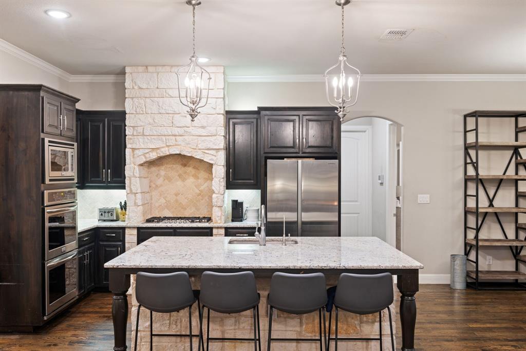 251 Hlavek Road Decatur, TX 76234 - Photo 16 of 33 a kitchen with stainless steel appliances granite countertop a kitchen island a stove a chandelier and a refrigerator