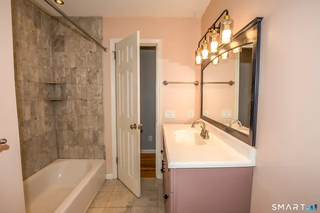a bathroom with a tub a sink and a mirror